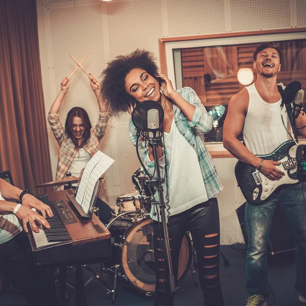 Student musicians playing and singing together in a practice room